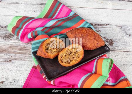 Kibbeh auf weißem Holzhintergrund. Kibbeh ist ein beliebtes Gericht in der nahöstlichen Küche. Gefüllte Fleischbällchen Essen, Falafel, icli Kofta, Quibe. Draufsicht. E Stockfoto