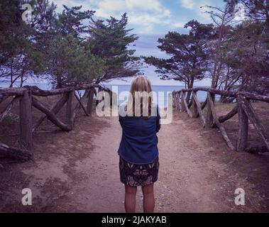 Dame auf dem Rücken blickt auf das Meer an einer Küstenstraße in Girona. Stockfoto