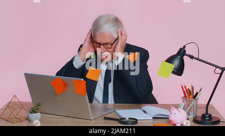 Müde erschöpft Müdigkeit Senior Business man Büroangestellte Manager sitzt im Bürotisch mit Laptop Haftnotizen Sticks mit vielen Aufgaben Beschriftung helfen, fühlt sich traurig Langeweile überarbeitetes Multitasking Stockfoto
