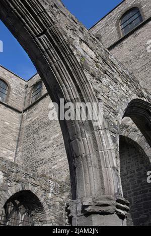 Freiliegende gotische Bögen in einem stillgelegten Teil der St. Audeon's Church, in Dublin mit der modernen katholischen Kirche dahinter. Einer der ältesten bestehenden chu Stockfoto