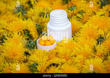 Vitamine in den Delelionen. Eine Flasche mit gelben Pillen in den Blumen des Dandelions, Nahaufnahme Stockfoto