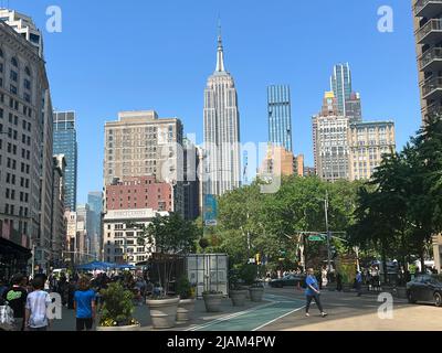 Blick auf das Empire State Building inmitten anderer Gebäude südlich der 23. Street, wo Broadway und 5. Avenue sich durch den Madison Park in Manhattan, NYC, kreuzen. Stockfoto