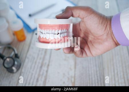 Doktor Hand hält Kunststoff Zahnzähne Modell auf dem Tisch Stockfoto