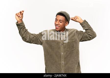 Junger Mann mit dunkler Haut, der auf weißem Hintergrund singt, tanzt und sich entspannt, genießt, Spaß hat, stellt euch vor, dass er ein berühmter Sänger ist Stockfoto