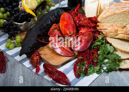 Geräucherter Stör, Hummer, Krebse, Brot, Käse und Früchte auf Holzoberfläche Stockfoto