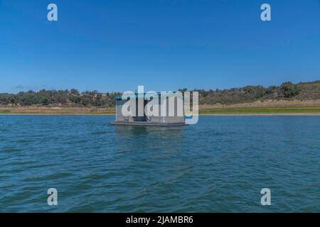 Eine öffentliche schwimmende Toilette auf einem See. Unter den Traufen der Struktur haben Schwalben von Klippen Nester gebaut. Stockfoto