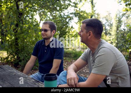 Lächelnde Männer sprechen und genießen friedlichen sonnigen Tag in der Natur Stockfoto