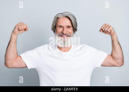 Portrait von attraktiven fröhlich starken grauhaarigen Mann metrosexual zeigt Muskeln isoliert über grauen Pastellfarben Hintergrund. Stockfoto