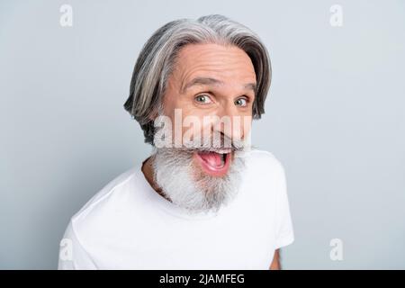 Foto von funky beeindruckt Rentner tragen weißes T-Shirt lächelnd offenen Mund isoliert grauen Hintergrund. Stockfoto