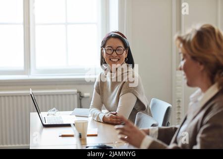 Fröhliche Professorin, die eine Kollegin im Stafroom ansieht Stockfoto