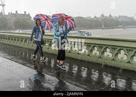 London, 31. Mai 2022. Zwei Frauen mit passenden Union Jack Schirmen trotzen den schweren Regengüssen auf der Westminster Bridge im Vorfeld der Platin-Jubiläumsfeiern, die am 2-5. Juni anlässlich der Thronbesteigung von Königin Elizabeth II. Im Jahr 1952 beginnen. Kredit. amer Ghazzal/Alamy Live Nachrichten Stockfoto