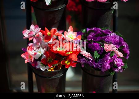 Blumen werden auf der Straße verkauft. Künstliche Blumen für den Friedhof. Details des Blumenladens. Blumen aus Kunststoff. Handel in Russland. Stockfoto