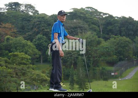 Erfahrener asiatischer Golfer posiert und bereitet sich auf den Abschlag beim Grün vor Stockfoto