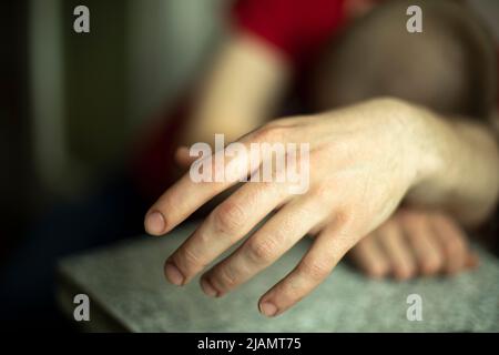 Hand der schlafenden Person. Guy schlief ein, als er sich hinsetzte. Hand des betrunkenen Kerls. Stockfoto