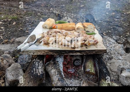 Gegrilltes Hähnchenfleisch auf Marmorstein in Holzfeuer in der Natur Stockfoto