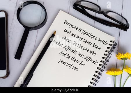 Motivationszitat auf schwarzem Notizbuch auf Holzschreibtisch - jeder kämpft gegen einen Kampf, den wir vielleicht nie kennen, sei der eine macht es schwierig, weniger abweiden Stockfoto