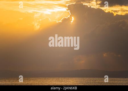 die dämmerung bei sonnenaufgang zeigt einen einfarbigen Mangrovenbaum in der Mitte des Ozeans an einem Strand mit der Sonne dahinter und den rotgoldenen Farben der Dämmerung Stockfoto