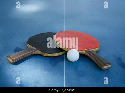 Schläger und Ball auf der blauen Tennistabelle. Sportliche Aktivitäten Stockfoto