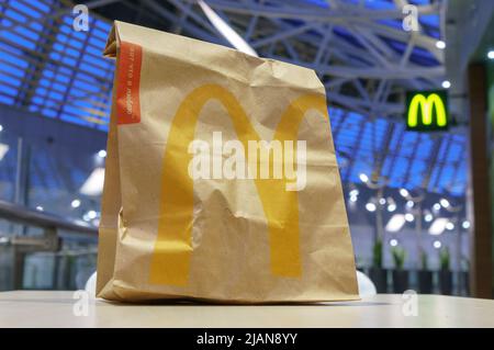 Moskau, Russland - 07. Februar 2019: McDonald’s braune Papiertüte mit verschwommenem Kiosk im Einkaufszentrum Stockfoto