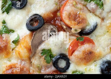 Makroaufnahme von italienischer Pizza mit Mozzarella und Kirschtomaten, Pilzen und roten Zwiebeln, Gewürzen, Ketchup und Paprika. Italienische Küche. Stockfoto
