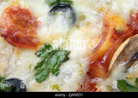 Makroaufnahme von italienischer Pizza mit Mozzarella und Kirschtomaten, Pilzen und roten Zwiebeln, Gewürzen, Ketchup und Paprika. Italienische Küche. Stockfoto