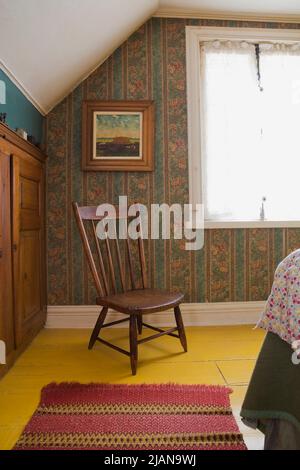 Antiker Stuhl und Möbel im Hauptschlafzimmer im Obergeschoss im alten, ca. 1810 Jahre alten Haus im kanadischen Cottage-Stil. Stockfoto