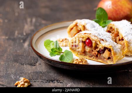 Hausgemachter duftender Strudel mit Äpfeln und Zimt auf einem Teller auf einem hölzernen Hintergrund mit Platz für Text, Stockfoto