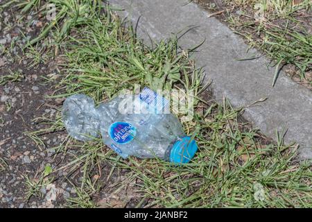 Zerkleinerte leere Flasche mit abgefülltem Wasser von Nestlé Pure Life am Rande der Landstraße. Für Umweltplastik, Einweg-Kunststoffe. Stockfoto