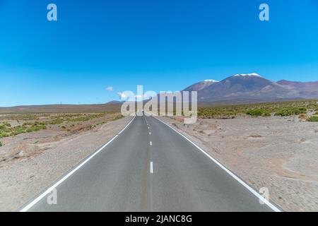 Straße in den Bergen zwischen den Klippen mit Blick auf die verschneiten Hügel Stockfoto