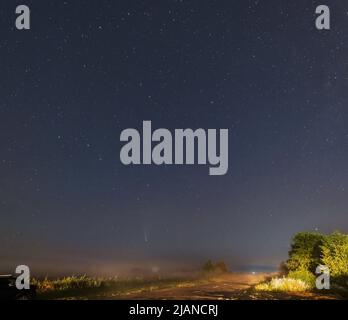 Komet Neowise C2020 F3, wie er im Sommerhimmel über einer Wiese in der Nähe der Landstraße, Region Lviv, Ukraine fliegt. Stockfoto