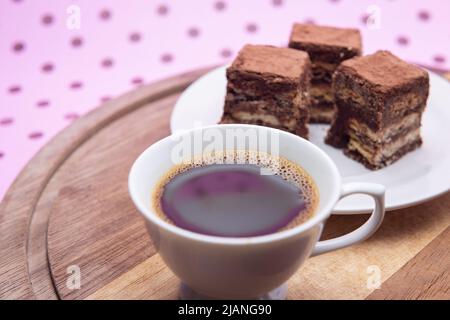 Goiânia, Goias, Brasilien – 31. Mai 2022: Eine Tasse Kaffee mit Stücken italienischen Strohhalms auf Holz auf einer rosa Oberfläche. Stockfoto