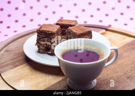 Goiânia, Goias, Brasilien – 31. Mai 2022: Eine Tasse Kaffee mit Stücken italienischen Strohhalms auf Holz auf einer rosa Oberfläche. Stockfoto