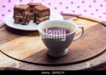 Goiânia, Goias, Brasilien – 31. Mai 2022: Eine Tasse Kaffee mit Stücken italienischen Strohhalms auf Holz auf einer rosa Oberfläche. Stockfoto