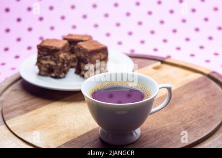 Goiânia, Goias, Brasilien – 31. Mai 2022: Eine Tasse Kaffee mit Stücken italienischen Strohhalms auf Holz auf einer rosa Oberfläche. Stockfoto