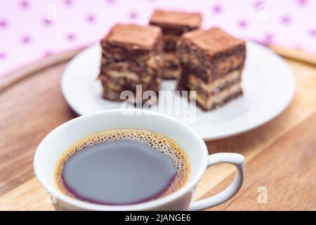 Goiânia, Goias, Brasilien – 31. Mai 2022: Eine Tasse Kaffee mit Stücken italienischen Strohhalms auf Holz auf einer rosa Oberfläche. Stockfoto