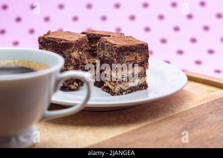 Goiânia, Goias, Brasilien – 31. Mai 2022: Eine Tasse Kaffee mit Stücken italienischen Strohhalms auf Holz auf einer rosa Oberfläche. Stockfoto