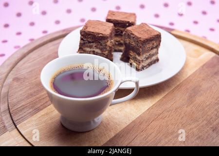 Goiânia, Goias, Brasilien – 31. Mai 2022: Eine Tasse Kaffee mit Stücken italienischen Strohhalms auf Holz auf einer rosa Oberfläche. Stockfoto