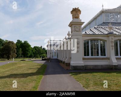Richmond, Greater London, England, Mai 18 2022: Royal Botanic Gardens Kew. Seitenansicht des gemäßigten Hauses inmitten von Rasen und Bäumen. Stockfoto