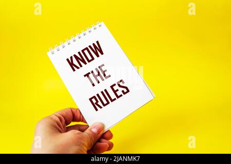 Visitenkarte in der Hand mit den Worten Ich kenne die Regeln, auf einem gelben Hintergrund. Die Hand des Geschäftsmannes. Business, kennen Sie das Regelkonzept. Speicherplatz kopieren. Stockfoto