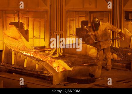 Mann, der den Fluss von geschmolzenem Kupfer aufrecht erhält, erste Quantum Minerals Kupferhütte Stockfoto