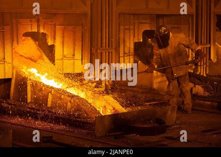 Mann, der den Fluss von geschmolzenem Kupfer aufrecht erhält, erste Quantum Minerals Kupferhütte Stockfoto