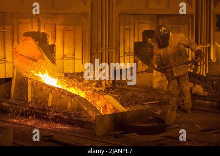 Mann, der den Fluss von geschmolzenem Kupfer aufrecht erhält, erste Quantum Minerals Kupferhütte Stockfoto
