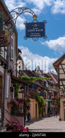 Eguisheim, Frankreich - 29. Mai 2022: Enge gepflasterte Straße mit bunten historischen Fachwerkhäusern Stockfoto