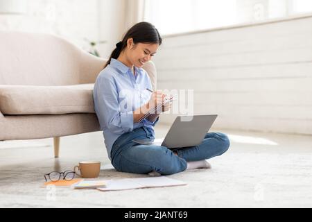 Chinesische Studentin, die zu Hause studiert, mit einem Notebook Stockfoto