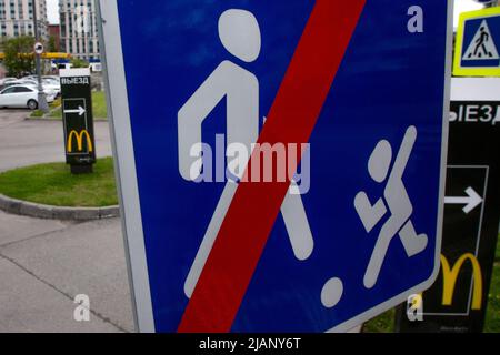 Moskau, Russland. 28.. Mai 2022. Embleme der Fast-Food-Restaurantkette McDonald's und das Straßenschild „das Ende der Wohnzone“ am Eingang zum Parkplatz Makavto in Moskau, Russland Stockfoto