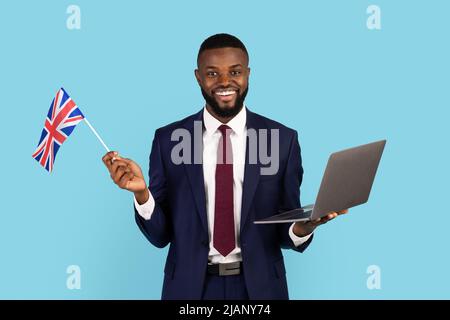 Schöner Schwarzer Geschäftsmann In Anzug Holding Laptop Und Britische Flagge Stockfoto