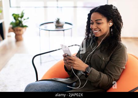 Lächelnde schwarze Dame mit Kopfbedeckung und Handy Stockfoto
