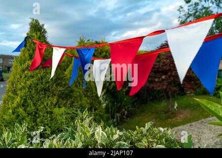 Bunting Flaggen in den Farben der britischen Flagge, weiß, rot und blau jeweils in verschiedenen Farben. Bunte dreieckige Fahnen wehen im Wind, um die zu feiern Stockfoto