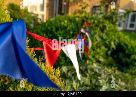 Bunting Flaggen in den Farben der britischen Flagge, weiß, rot und blau jeweils in verschiedenen Farben. Bunte dreieckige Fahnen wehen im Wind, um die zu feiern Stockfoto