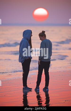 Ein Paar, das sich bei Ebbe, Sonnenuntergang, Brighton, England, Großbritannien, liebevoll am Strand umarmt. Stockfoto